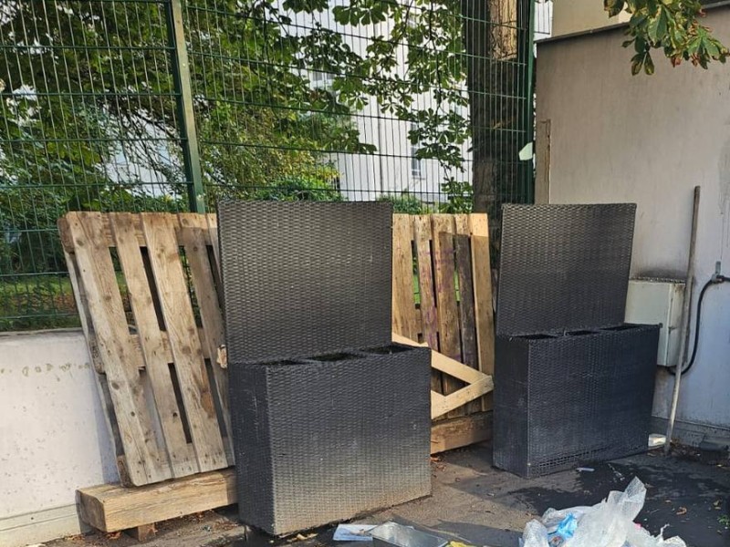 Ausgediente Polyrattan-Mülltonnenboxen und Europaletten an der Hofwand